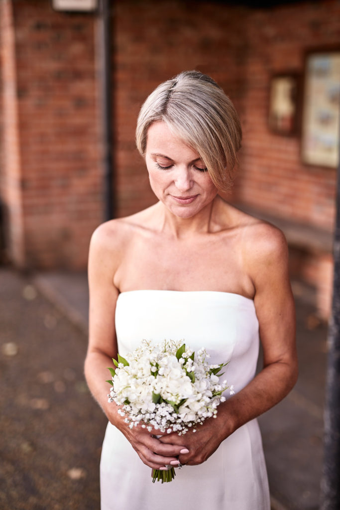 Bride in a strapless white dress looking down at her bouquet