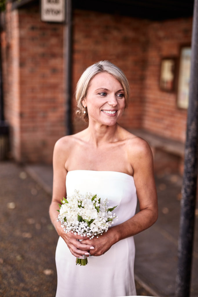 Bride smiling to one side as she holds her bouquet