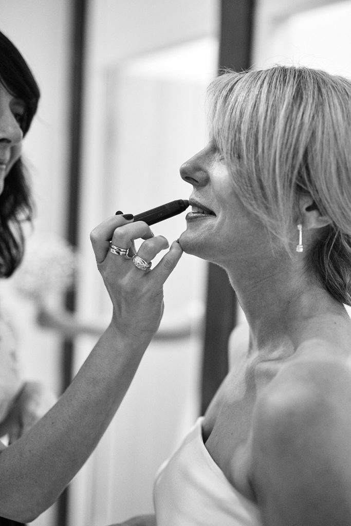 Black and white photo of the bride having her lipstick applied
