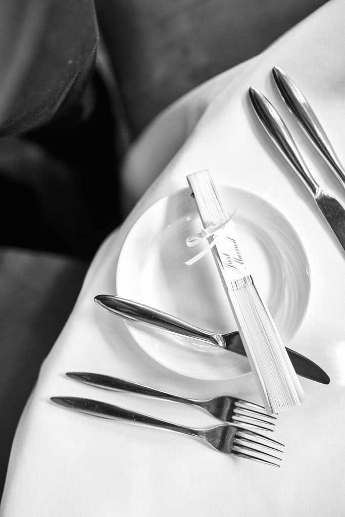 Black and white photo of a place setting with a folded paper fan