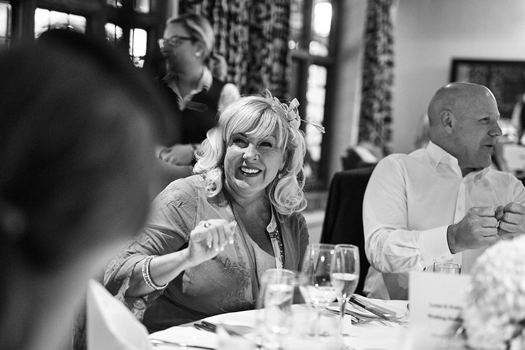 Black and white photo of guests laughing at their table