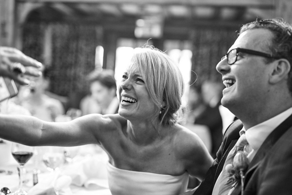 Black and white photo of the bride laughing with a guest at the table