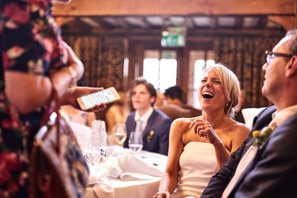 Bride laughing at the table as guests look on