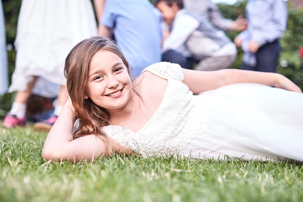 Flower girl lying on the grass, smiling