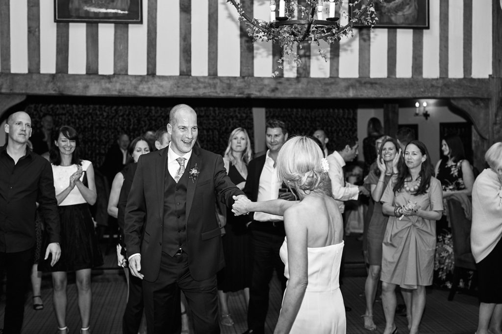 Black and white photo of the bride and groom on the dance floor as guests watch