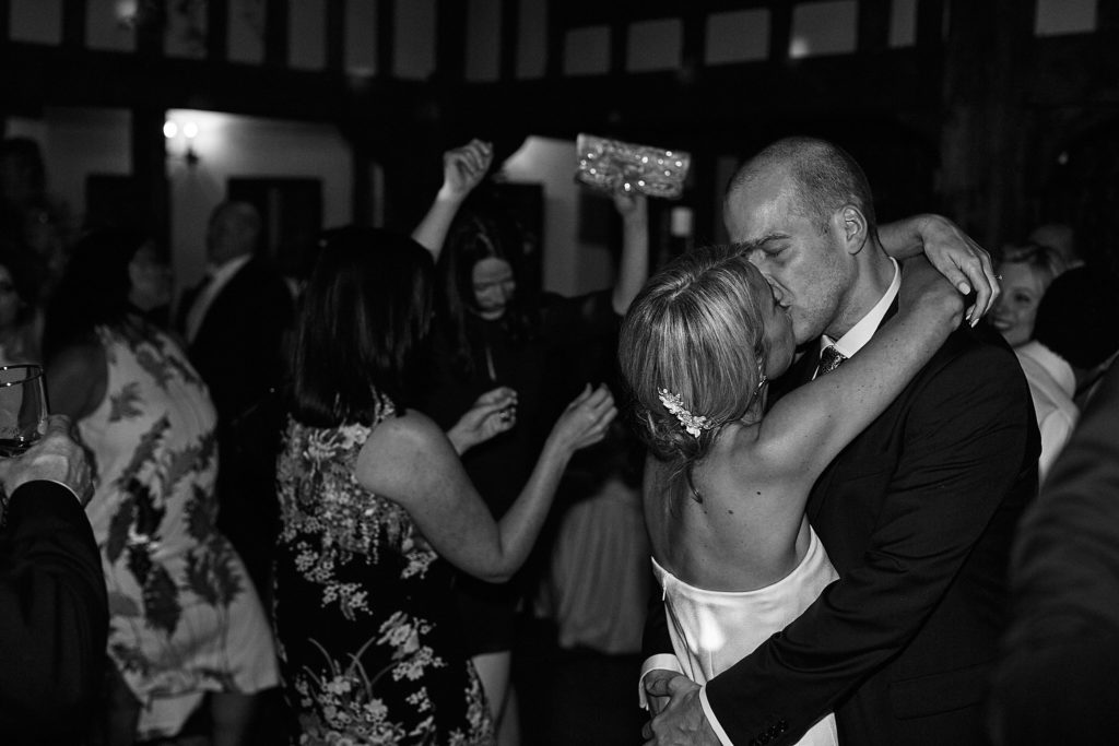 Black and white photo of the bride and groom kissing during their first dance
