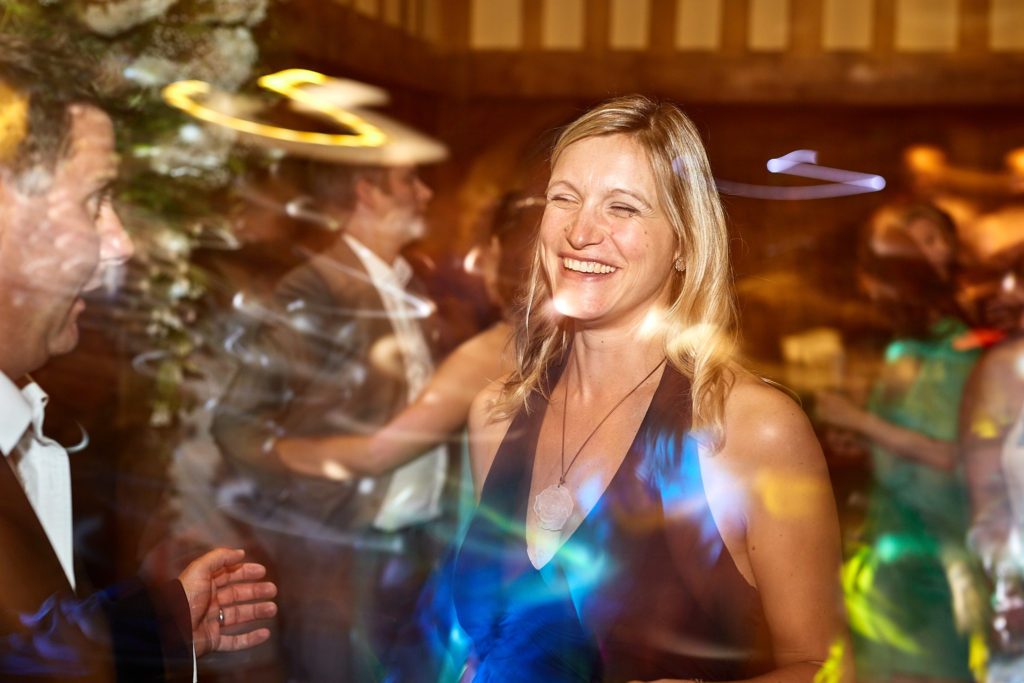 Wedding guest dancing among streaks of coloured light