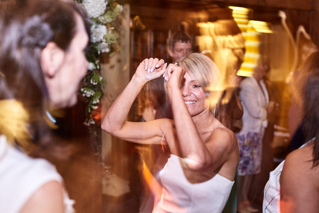 Bride dancing with her arms raised among her guests