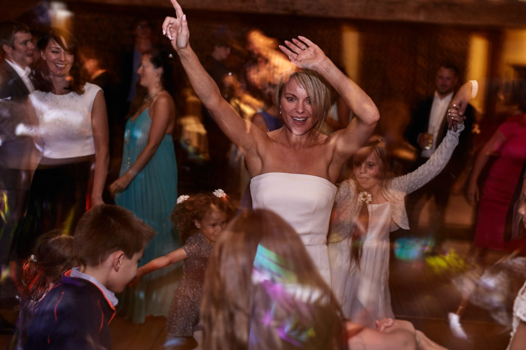 Bride dancing with her arm in the air surrounded by guests