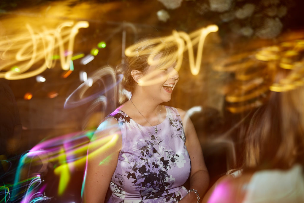Wedding guest dancing under swirling trails of light