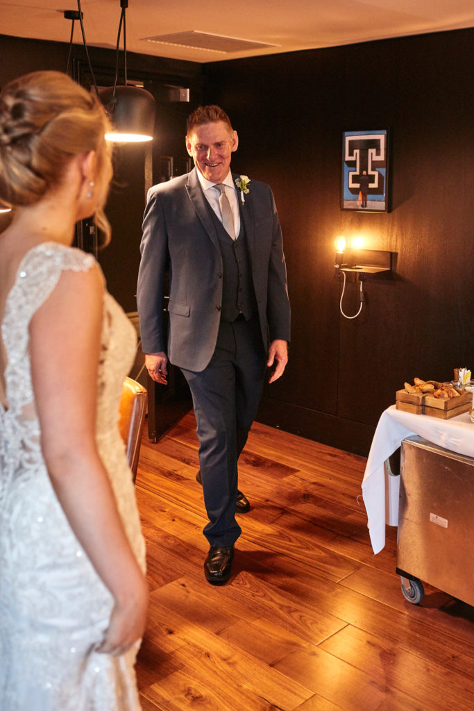 Man in a three-piece suit seeing the bride in her dress for the first time