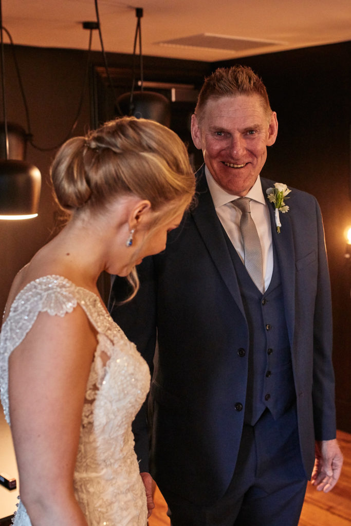 Bride looking down as a man in a navy suit smiles beside her