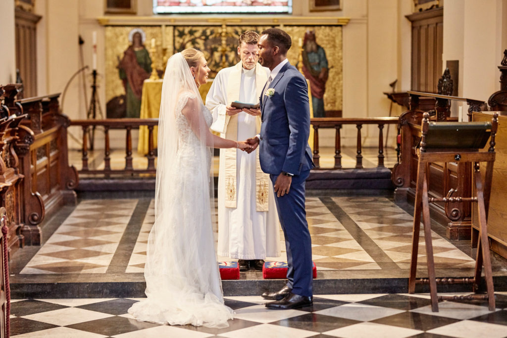 Bride and groom standing before the priest at the altar of a London church