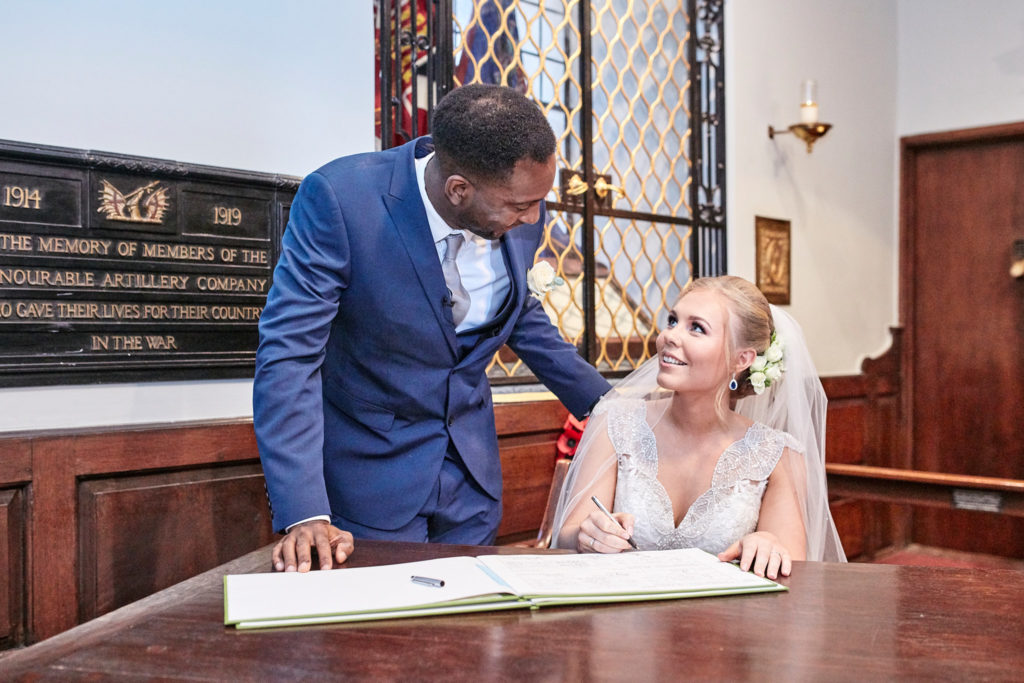 Groom standing as the bride signs the register
