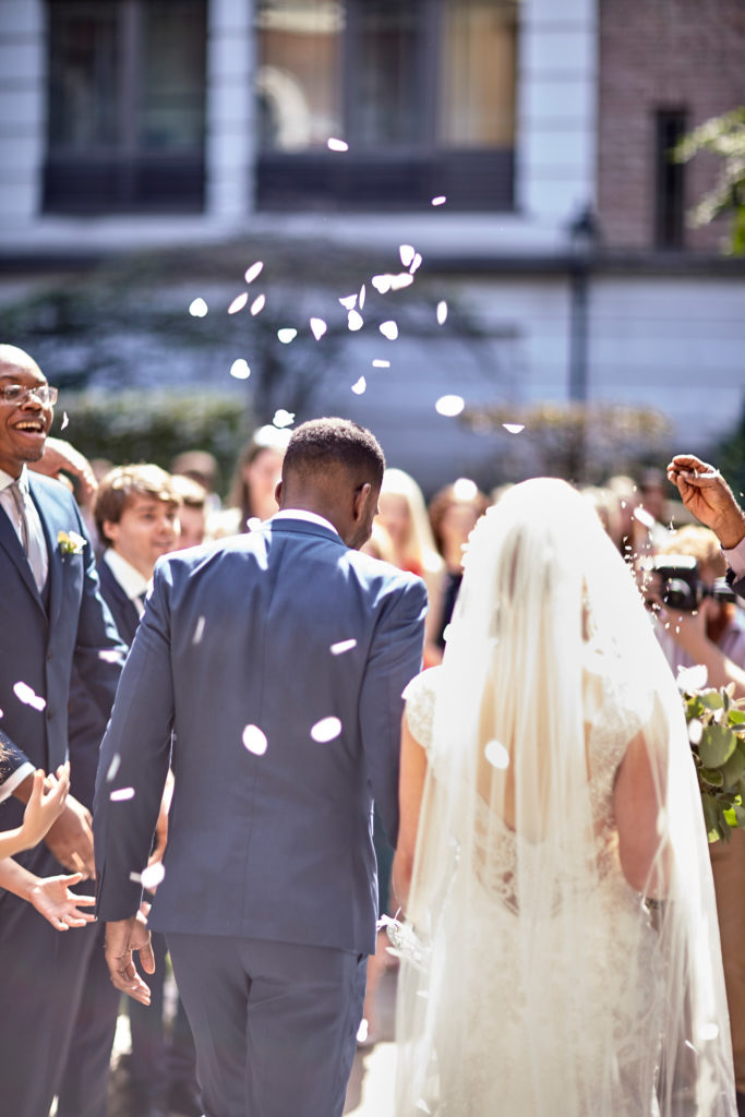 Bride and groom walking through confetti, seen from behind