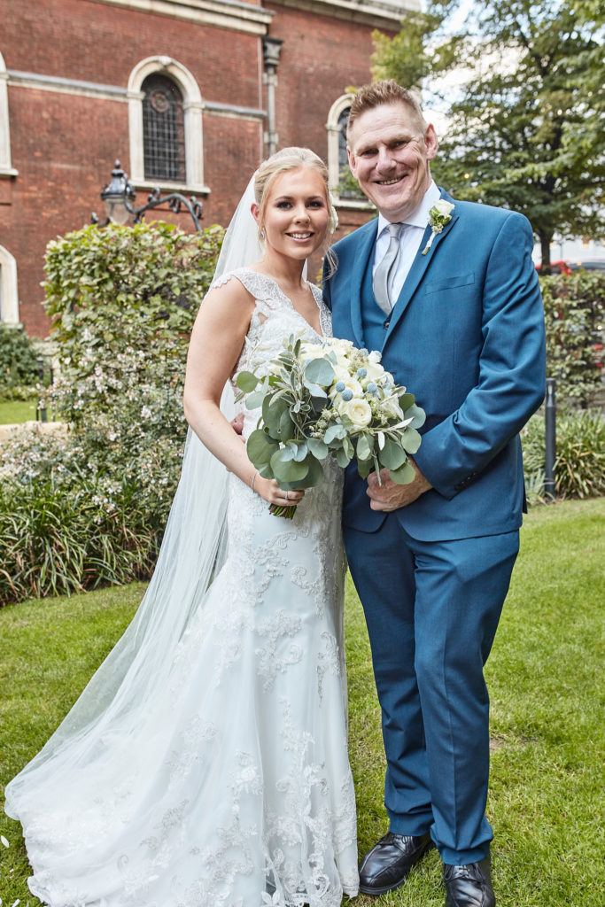 Bride with a man in a blue suit in the churchyard garden