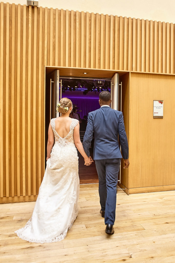 Bride and groom walking hand in hand into their wedding breakfast at the Andaz