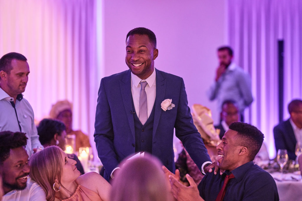Groom laughing with guests as he walks between the tables