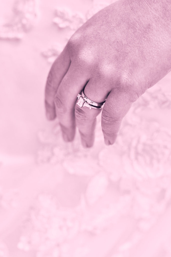 Close-up of the bride's hand and rings against her lace dress