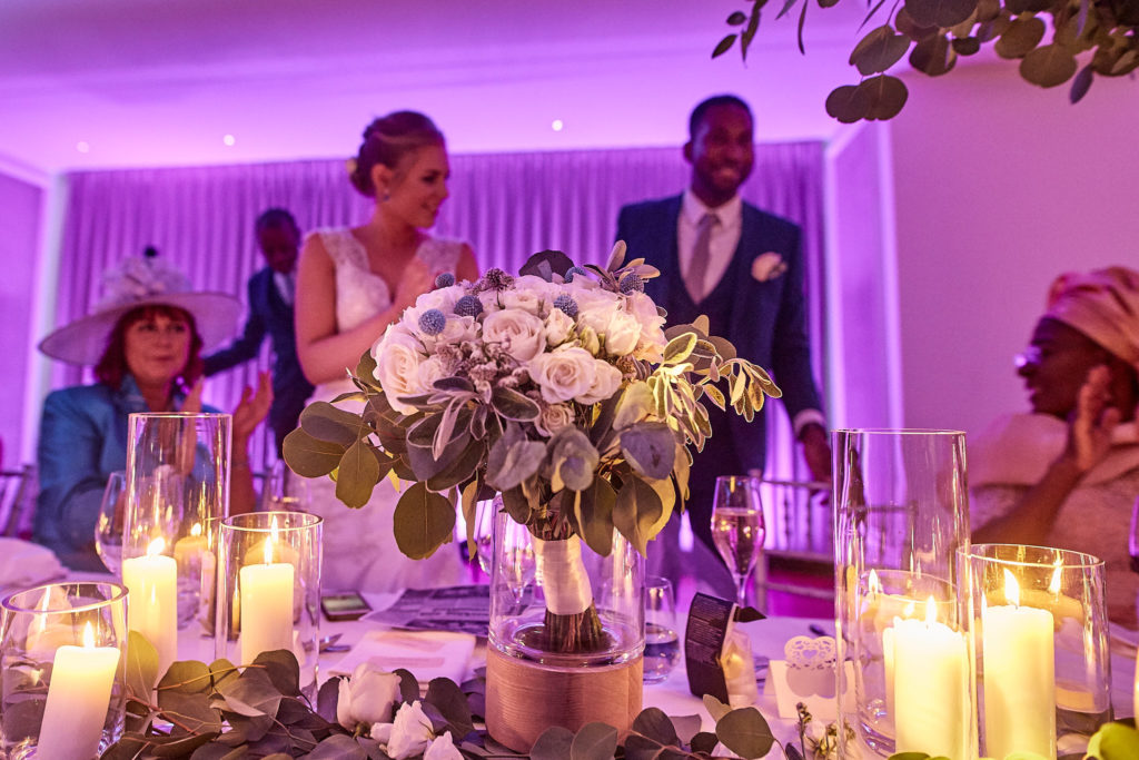 Bride and groom at the top table behind flowers and candles