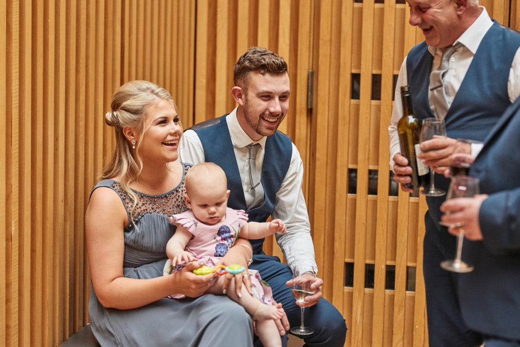 Couple with a baby chatting with a guest at the reception