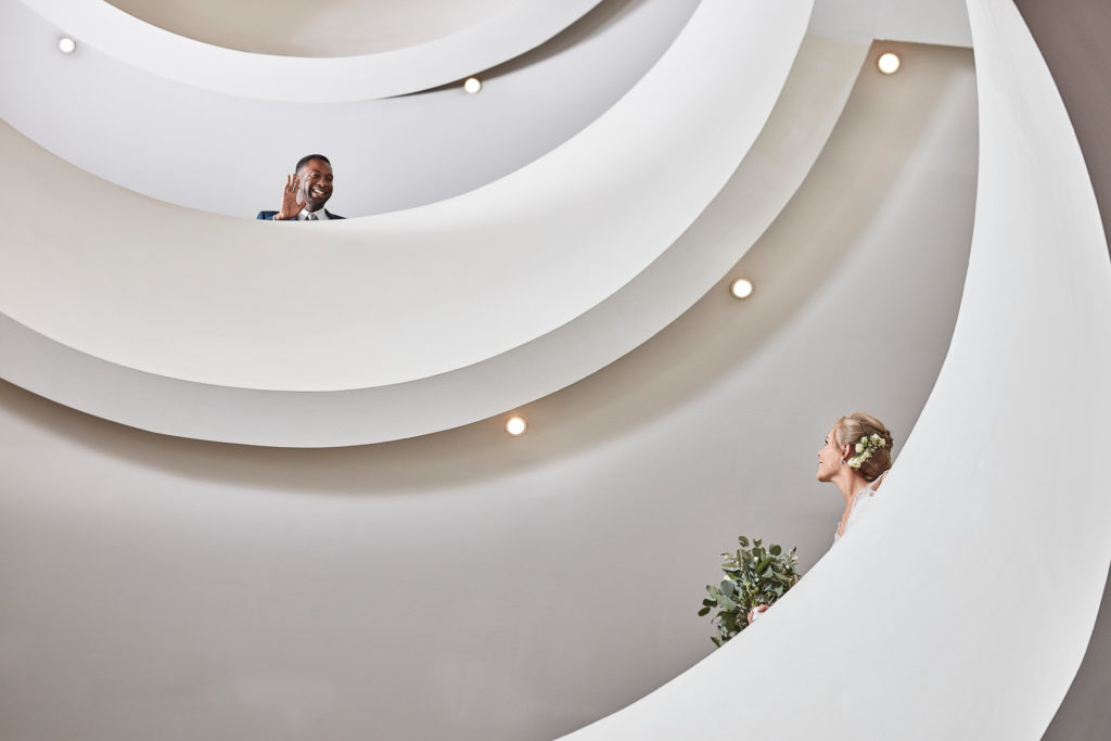 Bride and groom on a white spiral staircase at the Andaz, London, seen from above