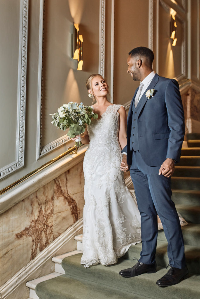 Bride and groom on a marble staircase at the Andaz hotel, London