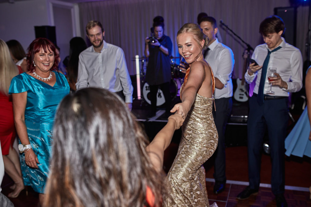 Bride in a gold sequinned dress on the dance floor with guests