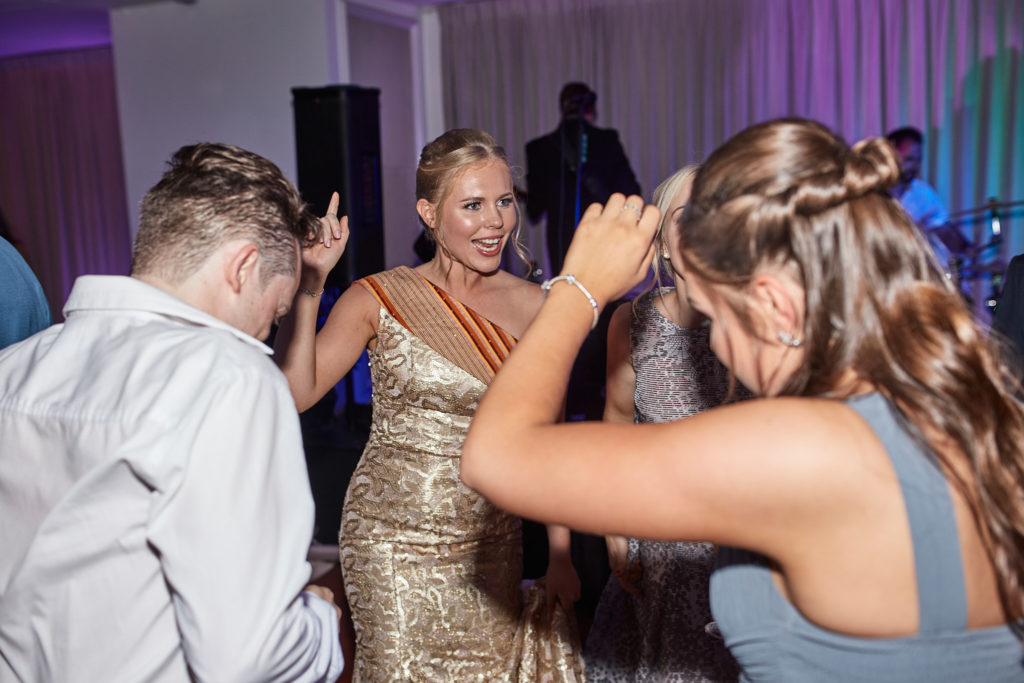Bride dancing with guests in her gold evening dress