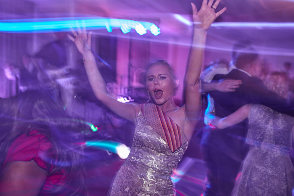 Bride dancing with her arms in the air among streaks of light