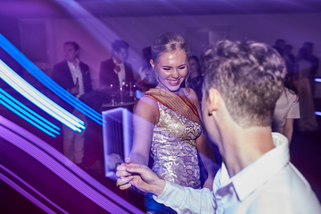 Bride dancing with a guest among trails of blue light
