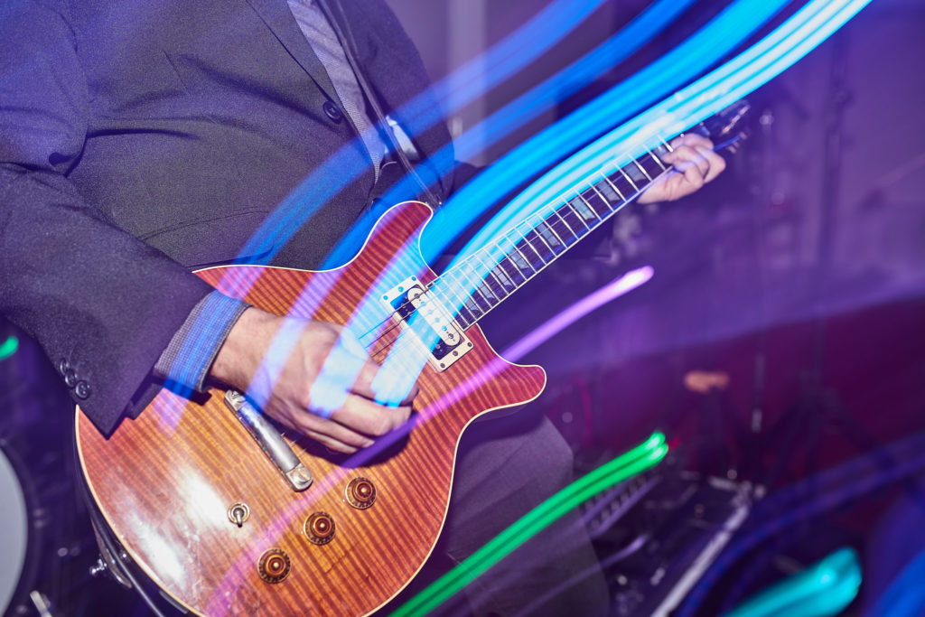 Close-up of a guitar being played among streaks of coloured light