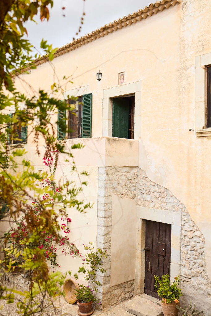 Sandstone finca building with green shutters and bougainvillea at Son Boronat