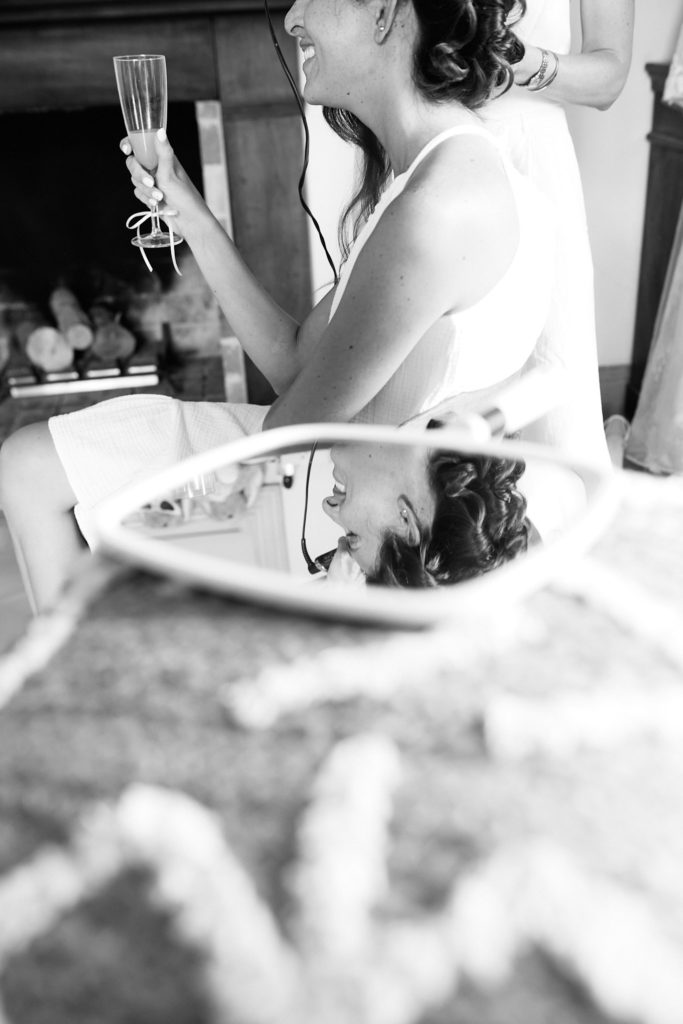 Black and white photo of a bridesmaid getting ready, reflected in a hand mirror