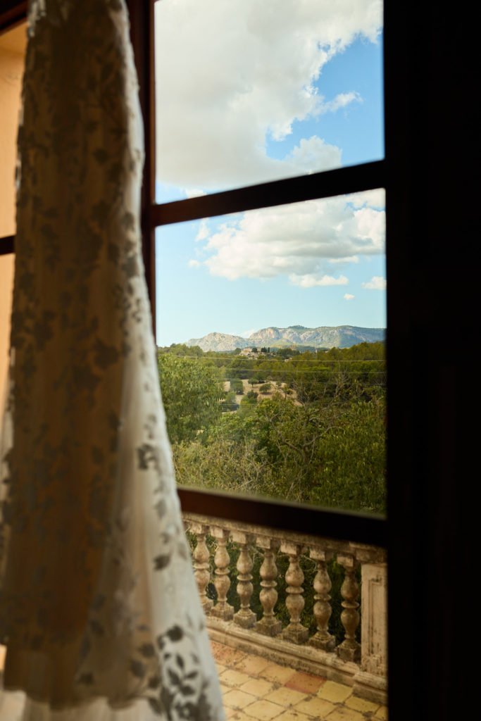 Close-up of the lace wedding dress beside a window with a view of the mountains