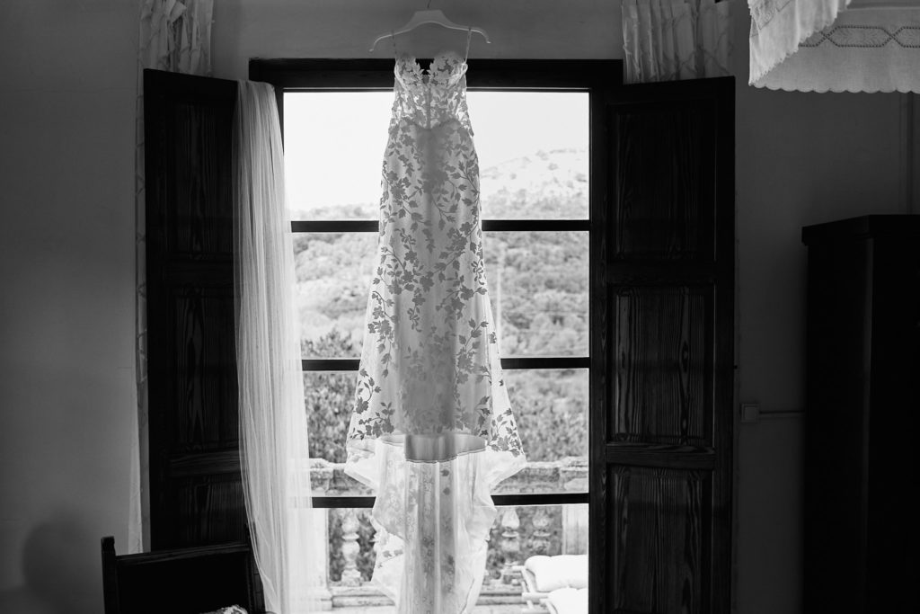 Black and white photo of the wedding dress hanging in a balcony doorway