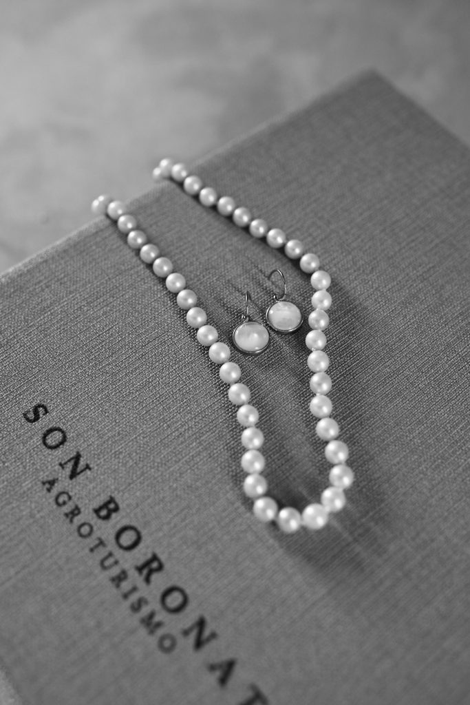 Black and white photo of a pearl necklace and earrings on a Son Boronat folder