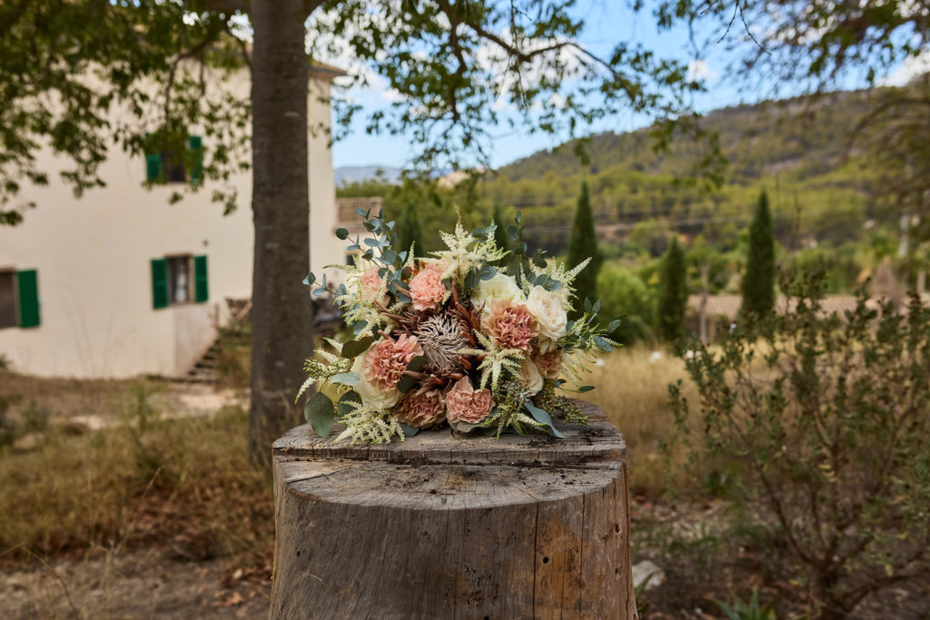 Bridal bouquet on a tree stump with the Mallorcan hills behind
