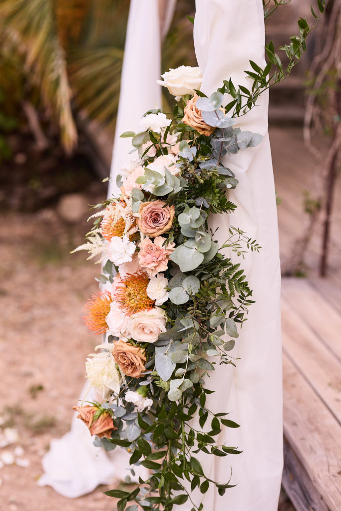 Flower garland of peach and cream roses on the ceremony arch