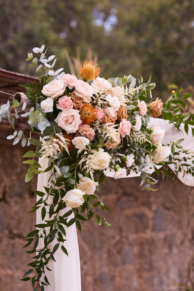 Flower arrangement of roses and proteas tied with white fabric