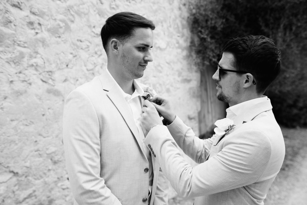 Black and white photo of a groomsman pinning on the groom's buttonhole