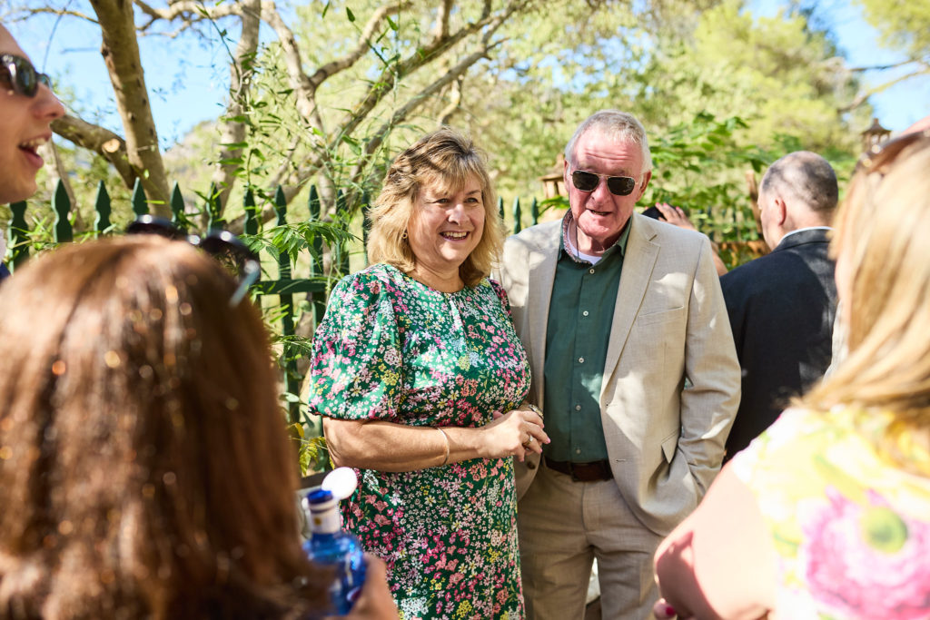 Wedding guests chatting in the sunshine before the ceremony