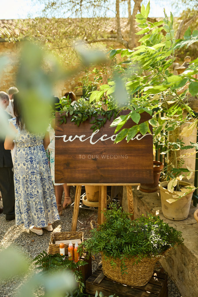 Wooden welcome sign among potted plants at the wedding at Son Boronat
