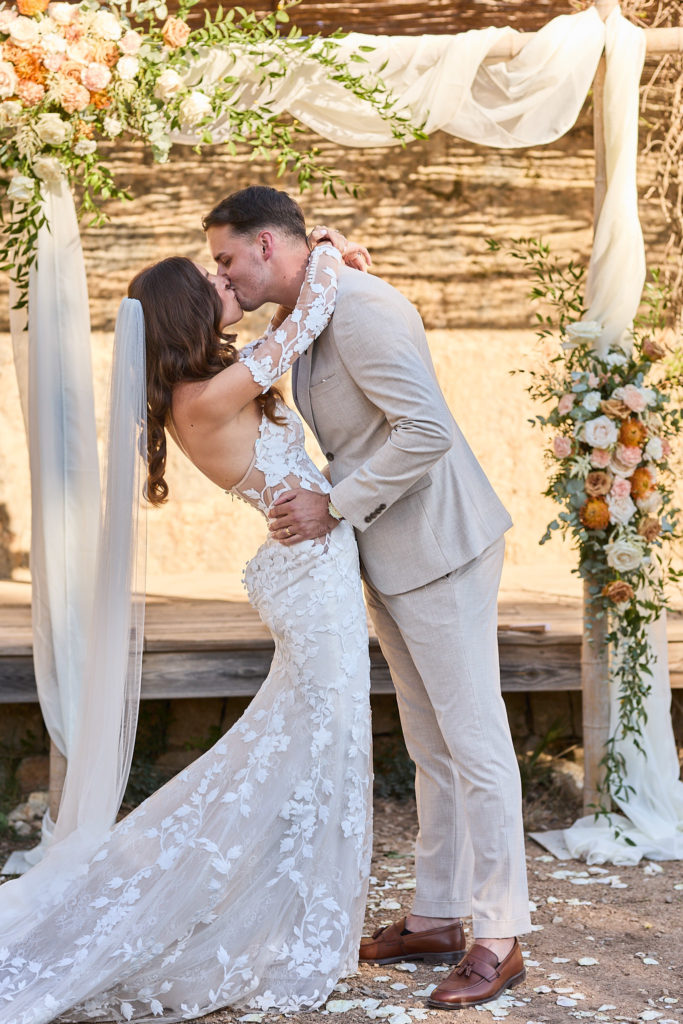 Bride and groom's first kiss under the flower arch at Son Boronat