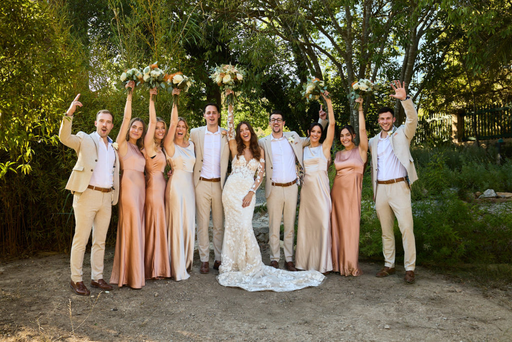 Bride and groom with bridesmaids and groomsmen cheering in the gardens at Son Boronat