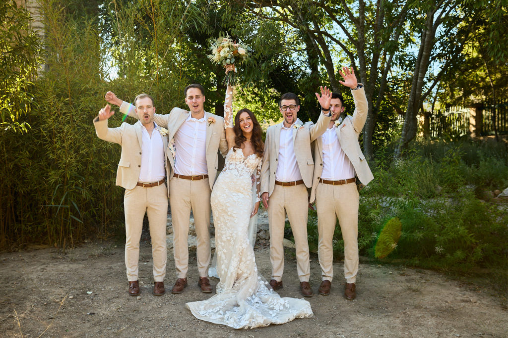 Bride and groom with the groomsmen cheering in beige suits