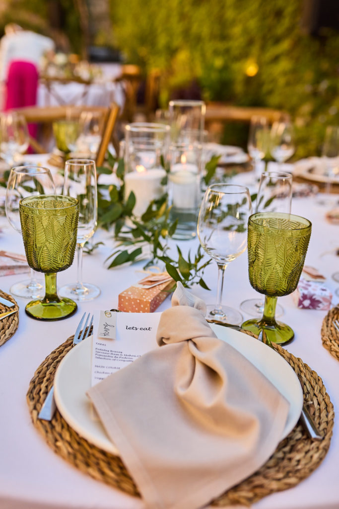 Place setting with a linen napkin, woven placemat and green goblets