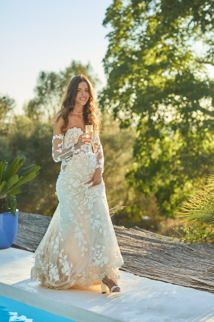 Bride smiling in her lace wedding dress beside the pool at Son Boronat