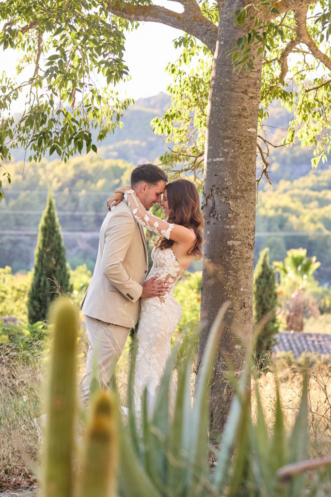 Bride and groom embracing beside a tree in the gardens at Son Boronat, Mallorca