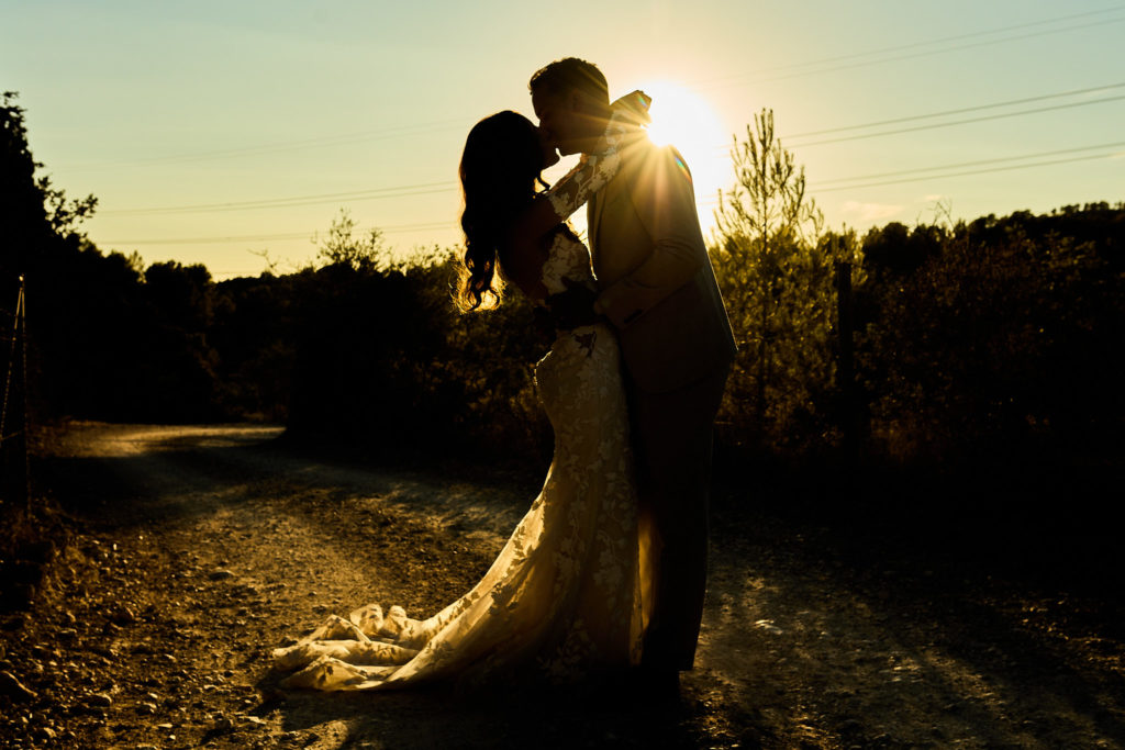 Bride and groom kissing in silhouette as the sun sets behind them in Mallorca